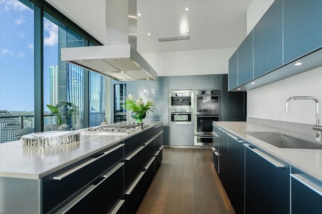 A large center island with waterfall-edge countertops doubles as a prep zone and social hub for gatherings. | Image 13