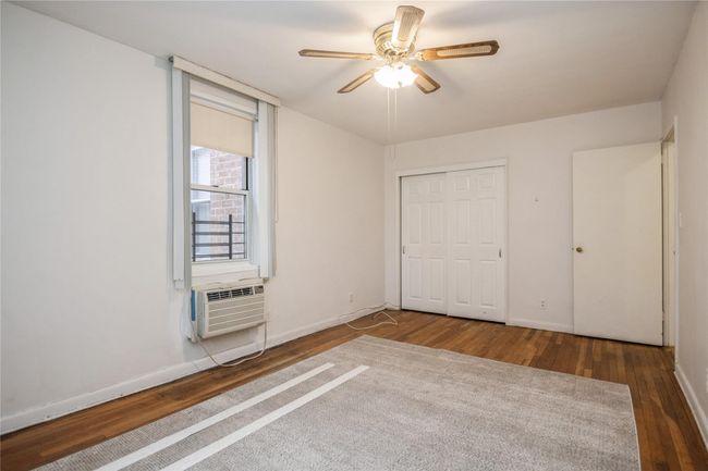 Unfurnished bedroom with wood finished floors, a closet, cooling unit, and a ceiling fan | Image 10