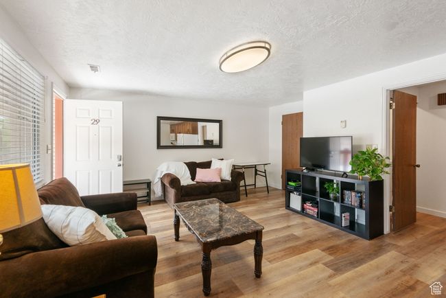 Living area with light wood-type flooring and a textured ceiling | Image 4