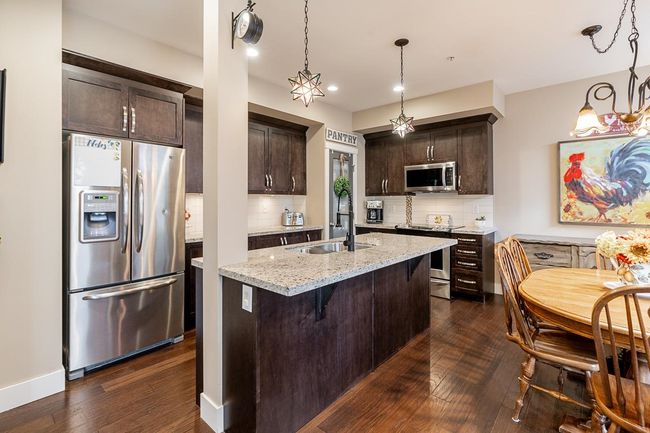Kitchen featuring stainless steel appliances, a sink, dark brown cabinetry, dark wood finished floors, and recessed lighting | Image 6