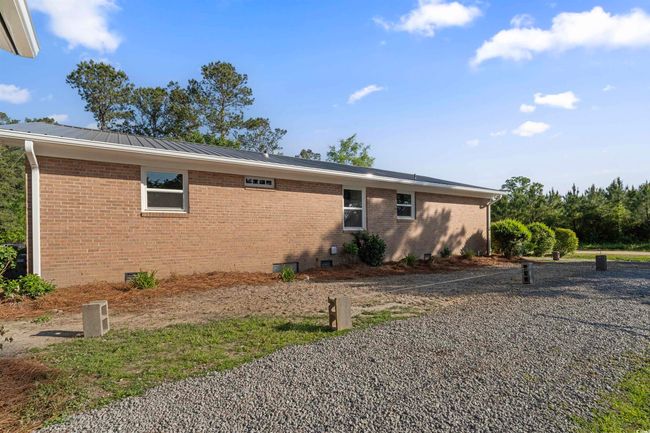 View of side of property with crawl space, brick siding, a metal roof, and a standing seam roof | Image 8