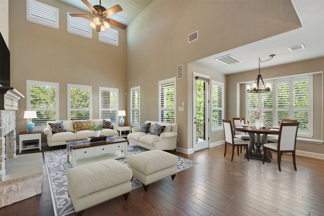 Living area with ceiling fan, a fireplace, a chandelier, a high ceiling, and dark wood-type flooring | Image 13