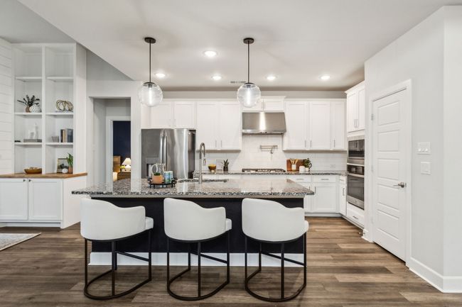 Kitchen featuring stainless steel appliances, under cabinet range hood, a sink, tasteful backsplash, and white cabinetry | Image 6