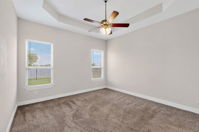 Carpeted empty room with a tray ceiling and a ceiling fan | Image 25