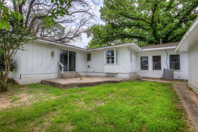 Rear view of house with entry steps, central AC unit, a yard, and board and batten siding | Image 30
