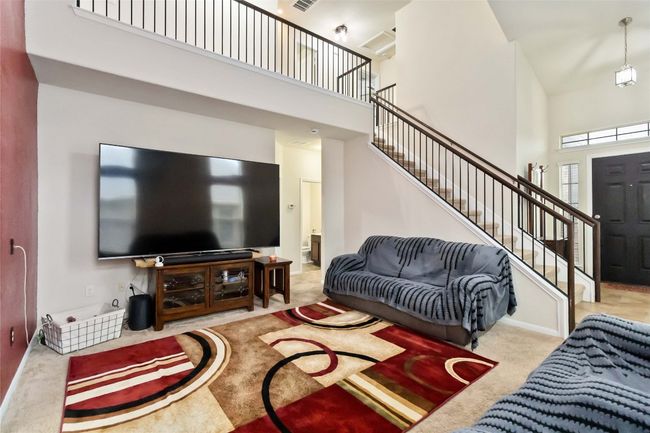Living room with a towering ceiling, carpet, and stairway | Image 4