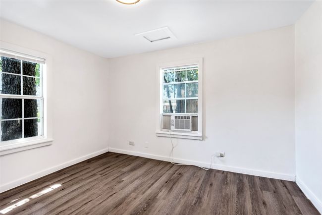 Unfurnished room with healthy amount of natural light, wood finished floors, attic access, and cooling unit | Image 14