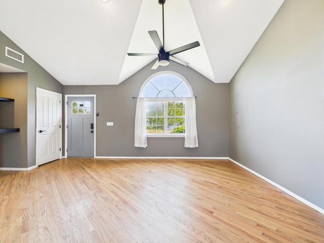 Unfurnished living room with ceiling fan, wood finished floors, and lofted ceiling | Image 13