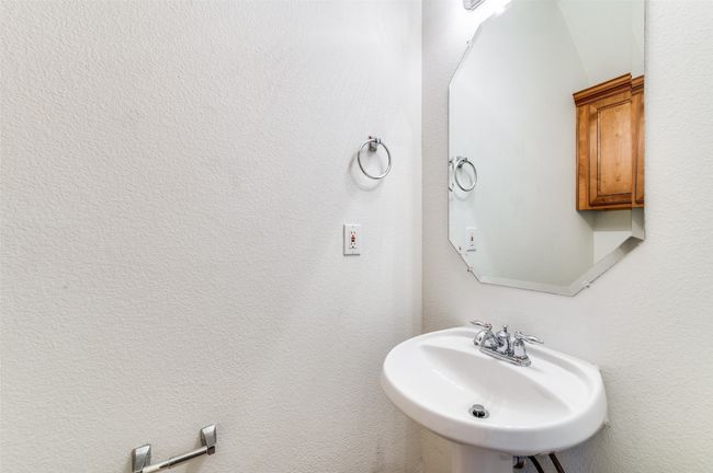 This stylish half bath features a classic pedestal sink that adds both charm and space-saving functionality. A sleek, framed mirror above the sink enhances the room’s brightness and creates an open, airy feel. Clean lines and a minimalist design make this powder room both practical and inviting—perfect for guests and everyday use. | Image 13