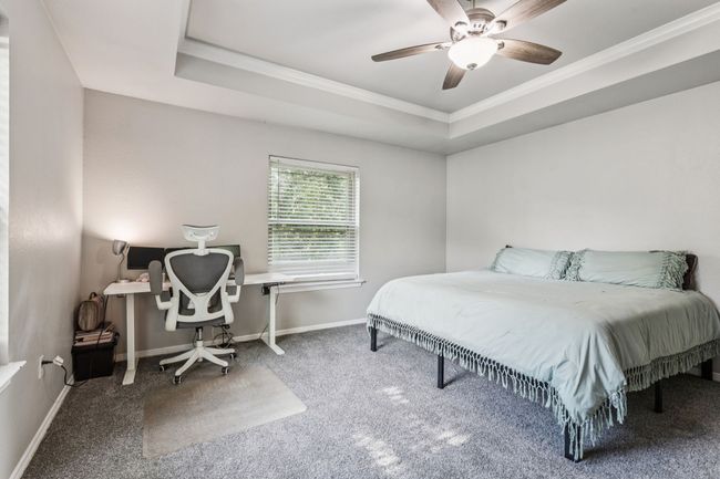 Carpeted bedroom with ornamental molding, a tray ceiling, and ceiling fan | Image 14