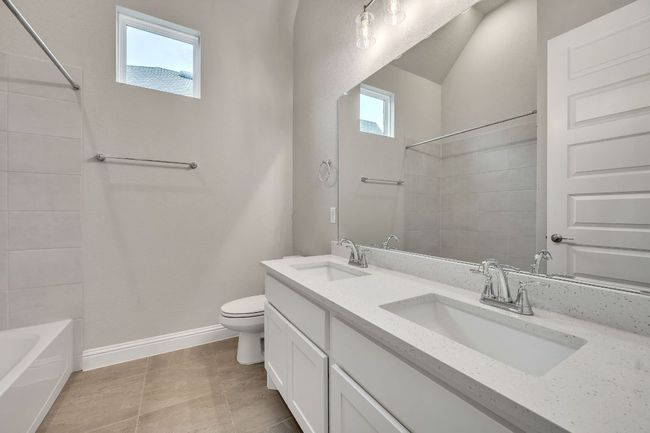 Bathroom featuring toilet, double vanity, baseboards, and a sink | Image 20