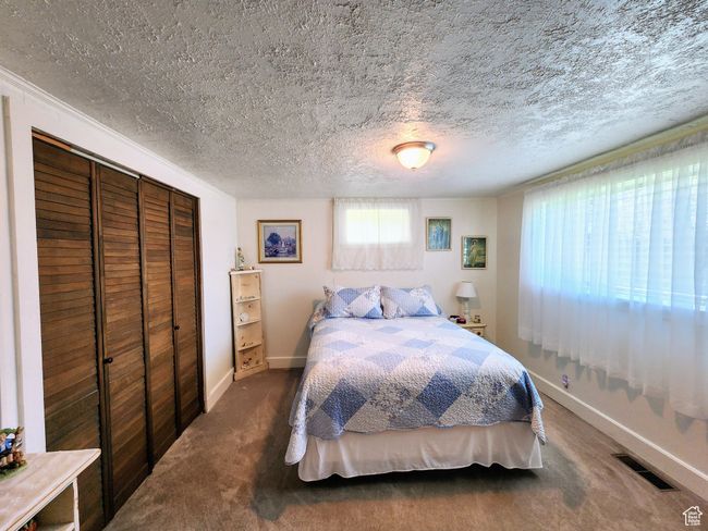 Bedroom featuring baseboards, a closet, a textured ceiling, and visible vents | Image 35