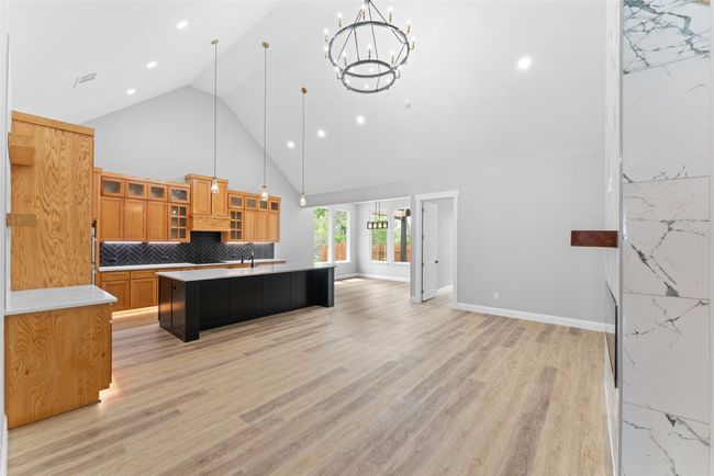 Kitchen featuring a kitchen island with sink, brown cabinetry, light countertops, high vaulted ceiling, and open floor plan | Image 11