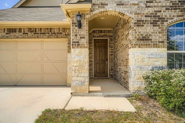 Entrance to property featuring brick siding, a garage, roof with shingles, and driveway | Image 5