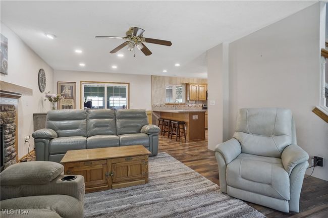 Living area with dark wood-style floors, a ceiling fan, a stone fireplace, and recessed lighting | Image 6