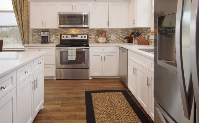 Kitchen with appliances with stainless steel finishes, decorative backsplash, and white cabinetry | Image 10