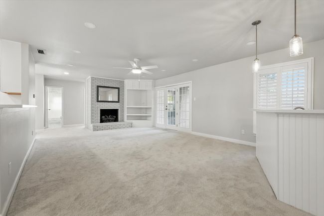 Unfurnished living room featuring light colored carpet, ceiling fan, baseboards, and a fireplace | Image 12