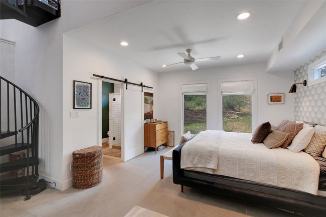 Primary bedroom with barn door bath entrance and spiral staircase to ensuite lounge/office | Image 16