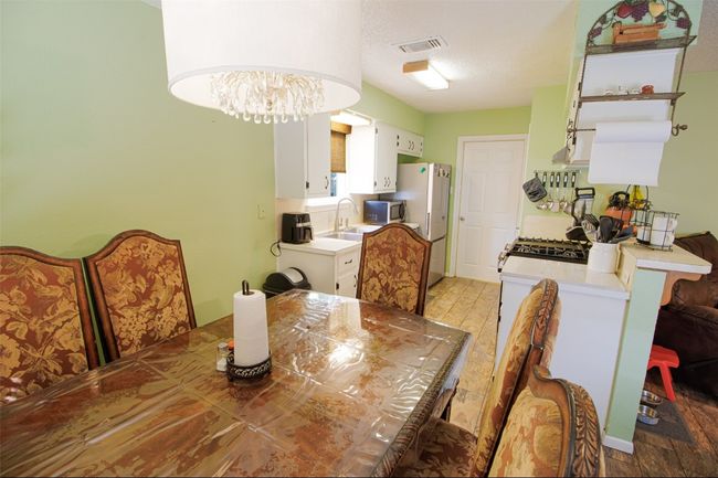 Dining room with a textured ceiling, visible vents, light wood-style floors, and a notable chandelier | Image 7