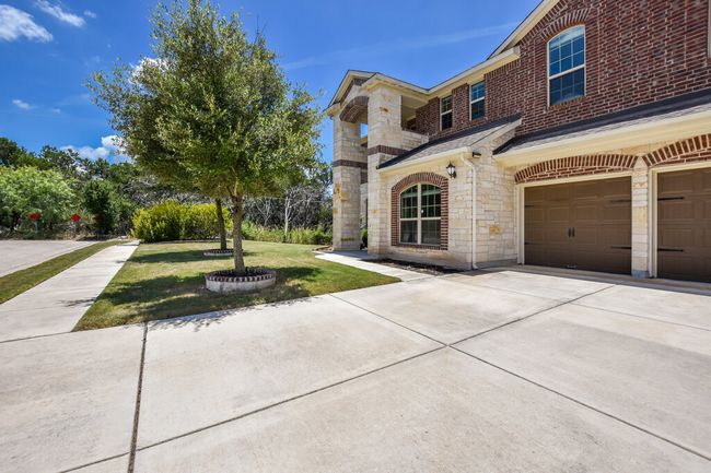 View of front of home with a front yard, stone siding, an attached garage, and concrete driveway | Image 5