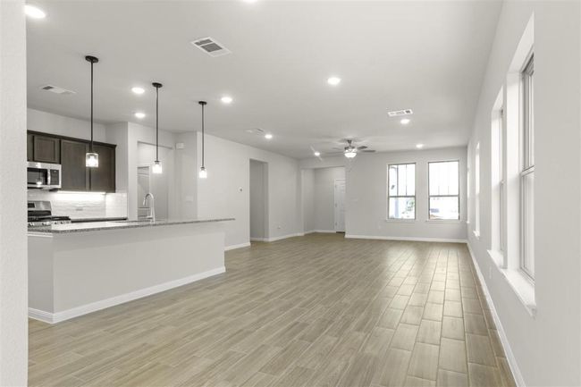 Unfurnished living room with light wood-style floors, visible vents, a sink, and a ceiling fan | Image 12