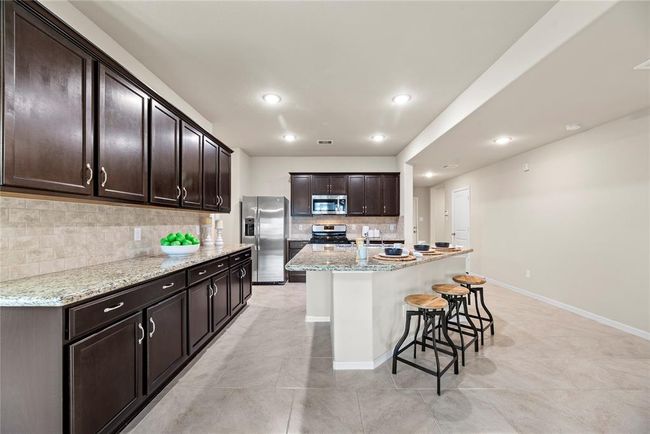 Granite countertops paired with a coordinating stone backsplash not only provide a durable and elegant surface for food preparation but also add a touch of luxury and sophistication to the kitchen. | Image 7