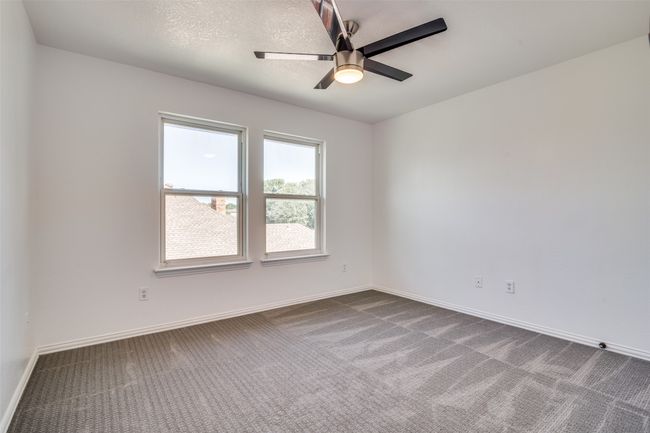 Empty room with dark carpet, ceiling fan, and baseboards | Image 20