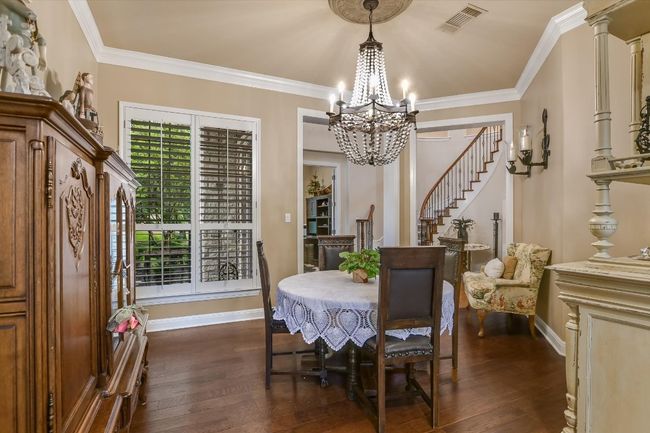 Formal Dining highlighted with a beaded chandelier, dark wood flooring, crown molding, and is near the kitchen. | Image 7