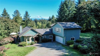 Elegant front door entry with stained glass side windows. Entrance to the home is from the West. Mt Rainier is in the background. Home has a finished attached double car garage and a separate detached two car garage/shop not shown in this photo. | Image 2