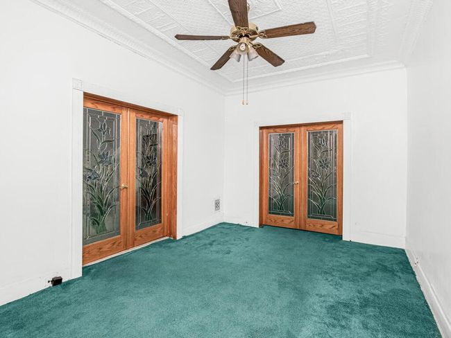 Carpeted empty room featuring crown molding, a ceiling fan, french doors, and baseboards | Image 4