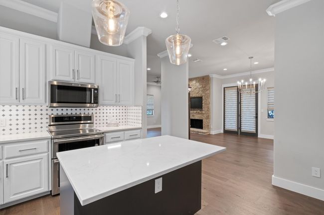 Kitchen with stainless steel appliances, a stone fireplace, ornamental molding, and tasteful backsplash | Image 11