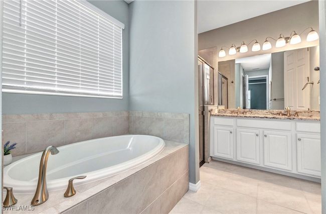 Bathroom featuring tile patterned flooring, vanity, a garden tub, and a stall shower | Image 39