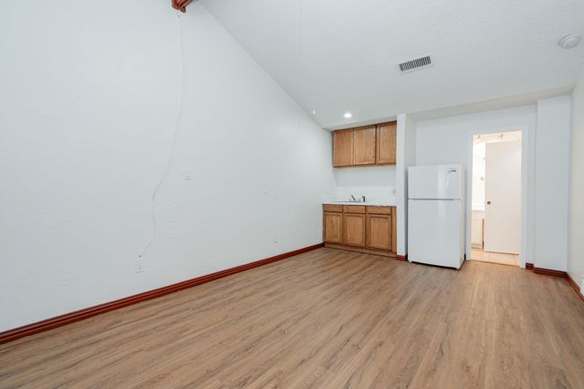 Kitchen featuring light wood-style flooring, visible vents, baseboards, freestanding refrigerator, and brown cabinets | Image 16