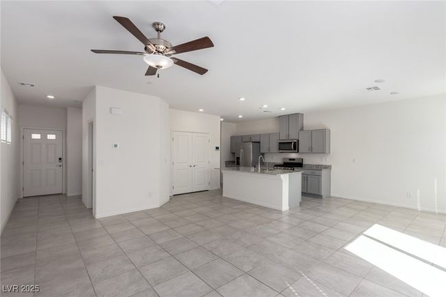 Kitchen featuring a ceiling fan, visible vents, gray cabinets, a kitchen island with sink, and stainless steel appliances | Image 5