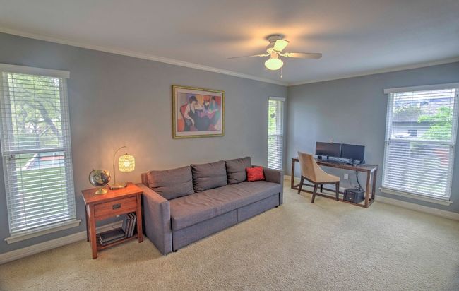 Bedroom featuring three windows, crown molding, baseboards, built-in shelving, ceiling fan, and light carpet | Image 34