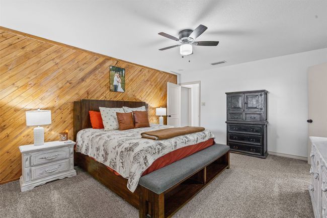 Bedroom with wood walls, carpet flooring, and ceiling fan | Image 16