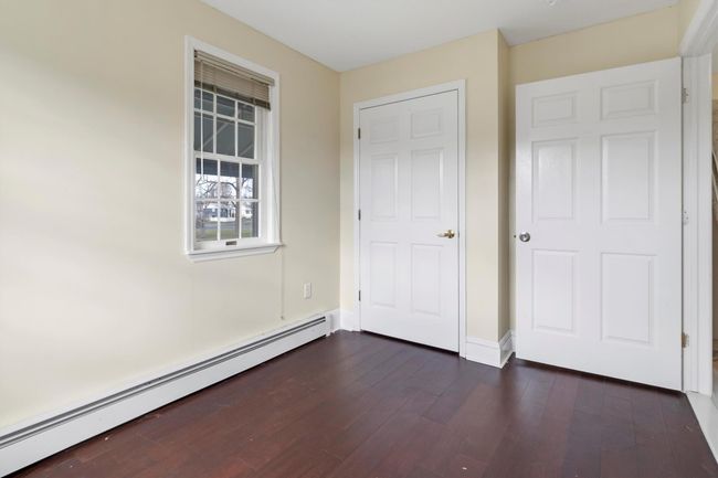 Unfurnished bedroom featuring baseboard heating, dark wood-style flooring, and baseboards | Image 32