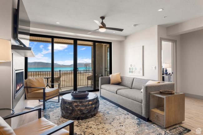 Living area featuring ceiling fan, wood finished floors, a lit fireplace, a water view, and recessed lighting | Image 49