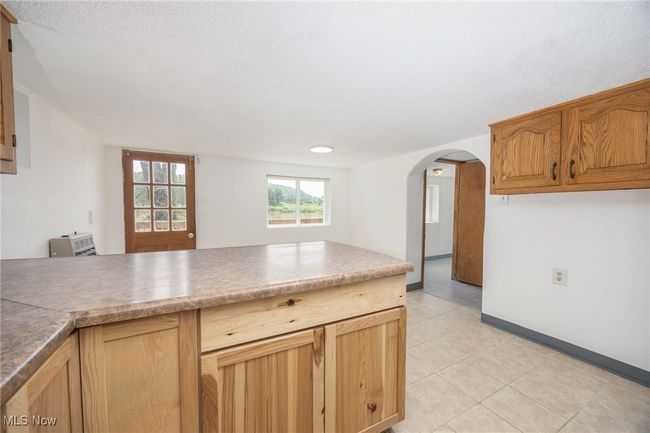 Kitchen with arched walkways, light tile patterned floors, baseboards, and a peninsula | Image 19