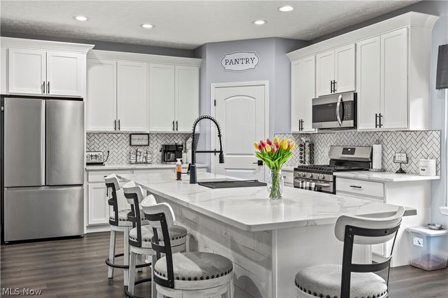 Kitchen with a center island with sink, dark hardwood / wood-style flooring, white cabinets, and appliances with stainless steel finishes | Image 15