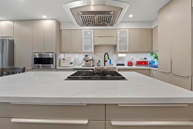 Kitchen with appliances with stainless steel finishes, exhaust hood, a sink, modern cabinets, and a center island | Image 6