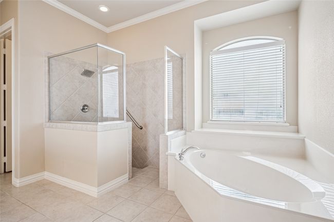 Ensuite primary bathroom with a walk in shower, crown molding, and tile floors | Image 21