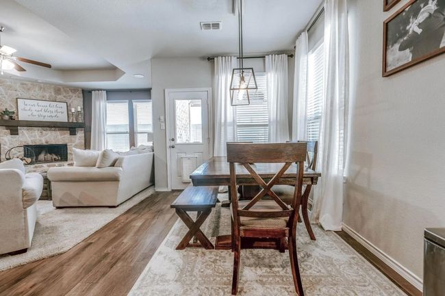 Dining area featuring a fireplace, wood finished floors, a ceiling fan, visible vents, and baseboards | Image 23