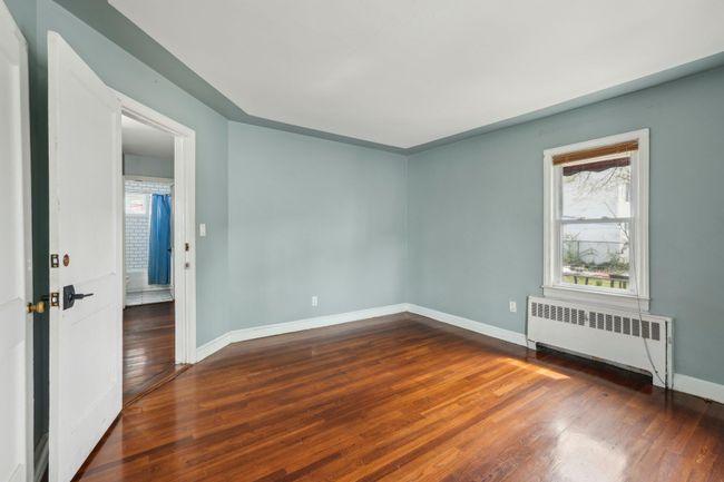 Empty room featuring baseboards, radiator, and dark wood finished floors | Image 10