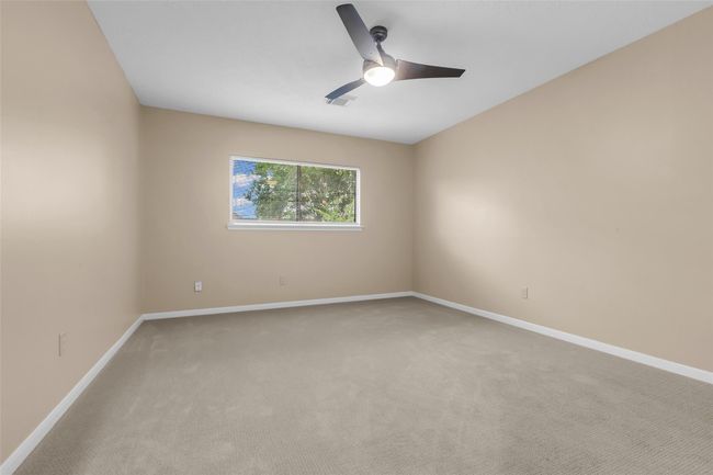 The primary suite located in the back of the home boasts new carpet, a large window and ceiling fan. | Image 17