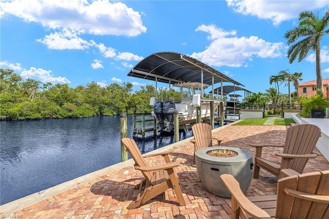 Dock area featuring boat lift, a fire pit, and a water view | Image 47