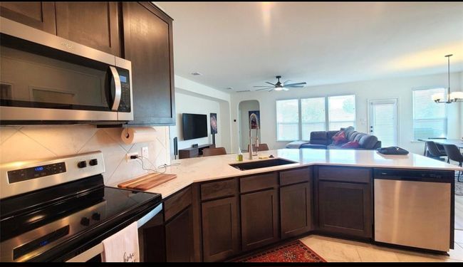 Kitchen with stainless steel appliances, open floor plan, dark brown cabinets, and arched walkways | Image 14