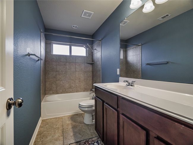 Bathroom featuring toilet, vanity, tub / shower combination, baseboards, and a textured wall | Image 10