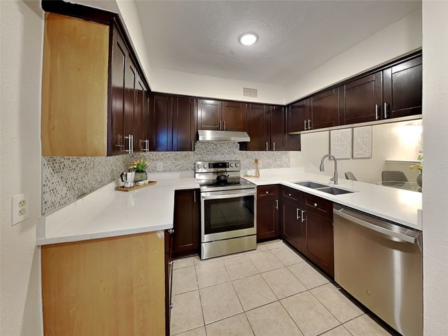 Kitchen featuring under cabinet range hood, visible vents, a sink, light tile patterned flooring, and appliances with stainless steel finishes | Image 11