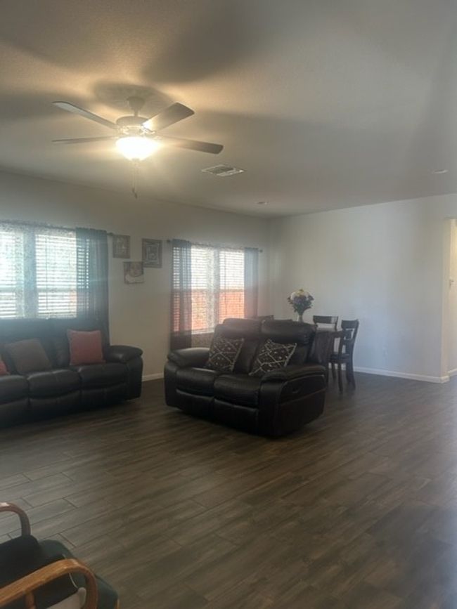 Living area featuring dark wood-type flooring, baseboards, ceiling fan, and visible vents | Image 11